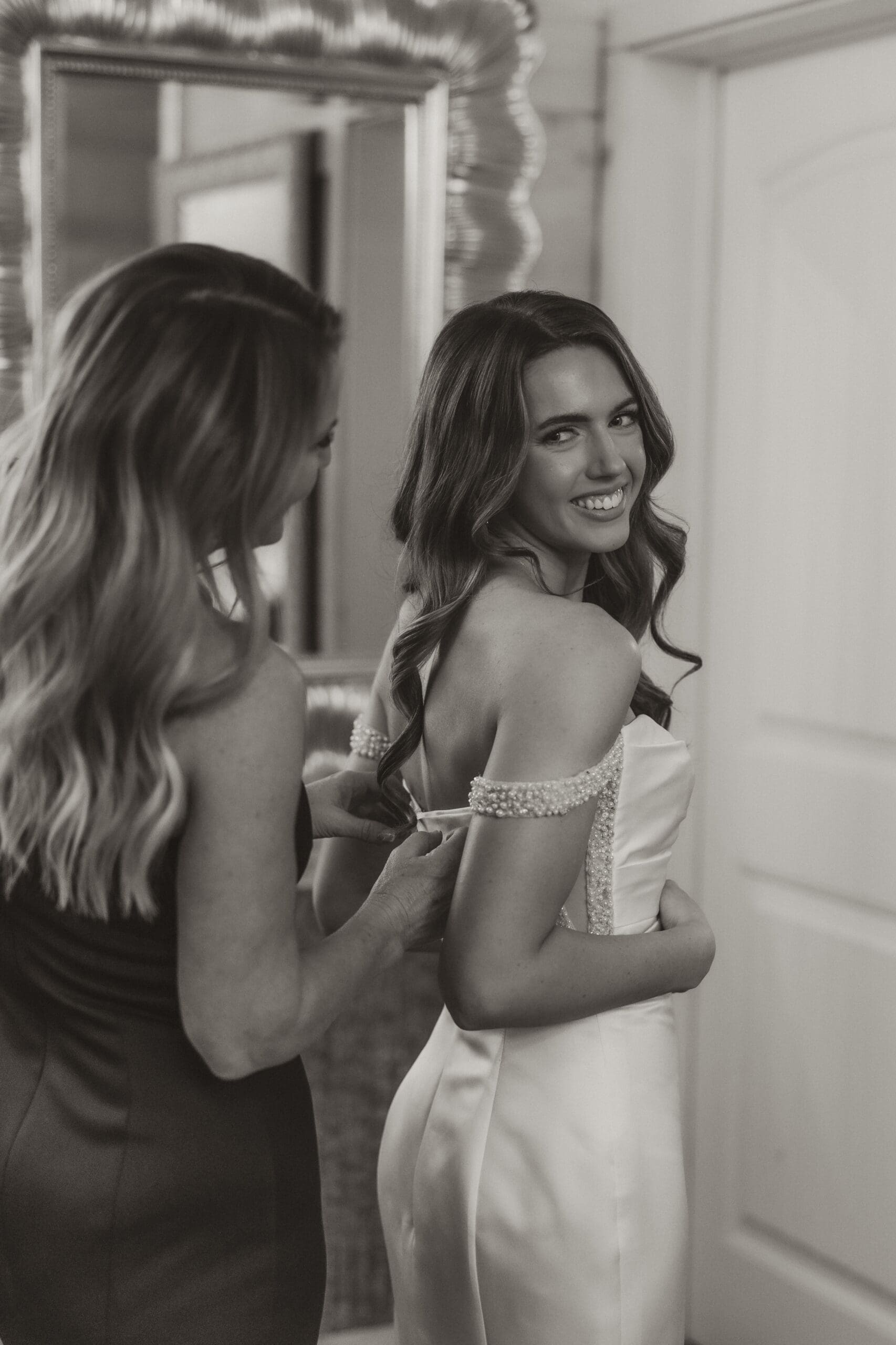 Mother of the bride helping her daughter into dress before winter wedding at The Silver Spoon Barn