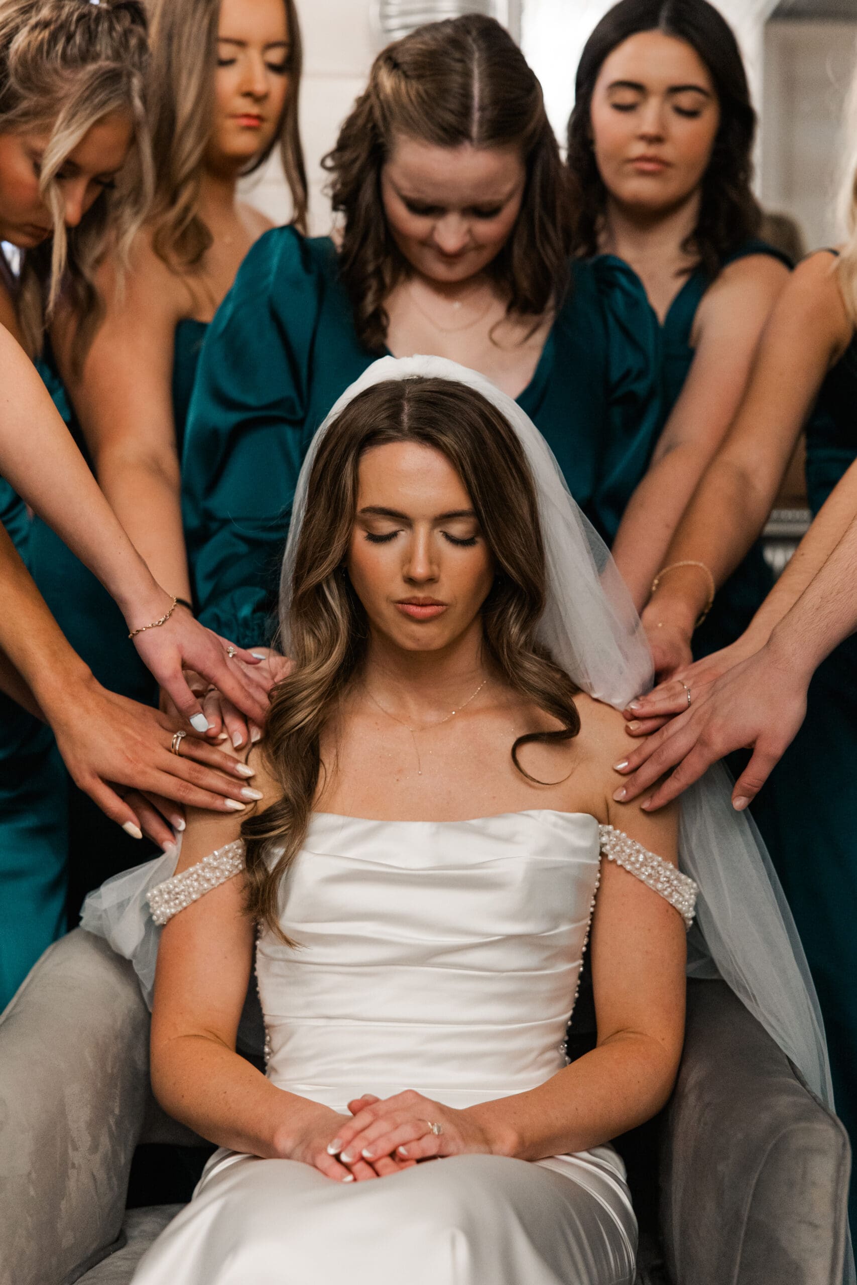 Bridesmaids praying over bride before winter wedding ceremony at The Silver Spoon Barn