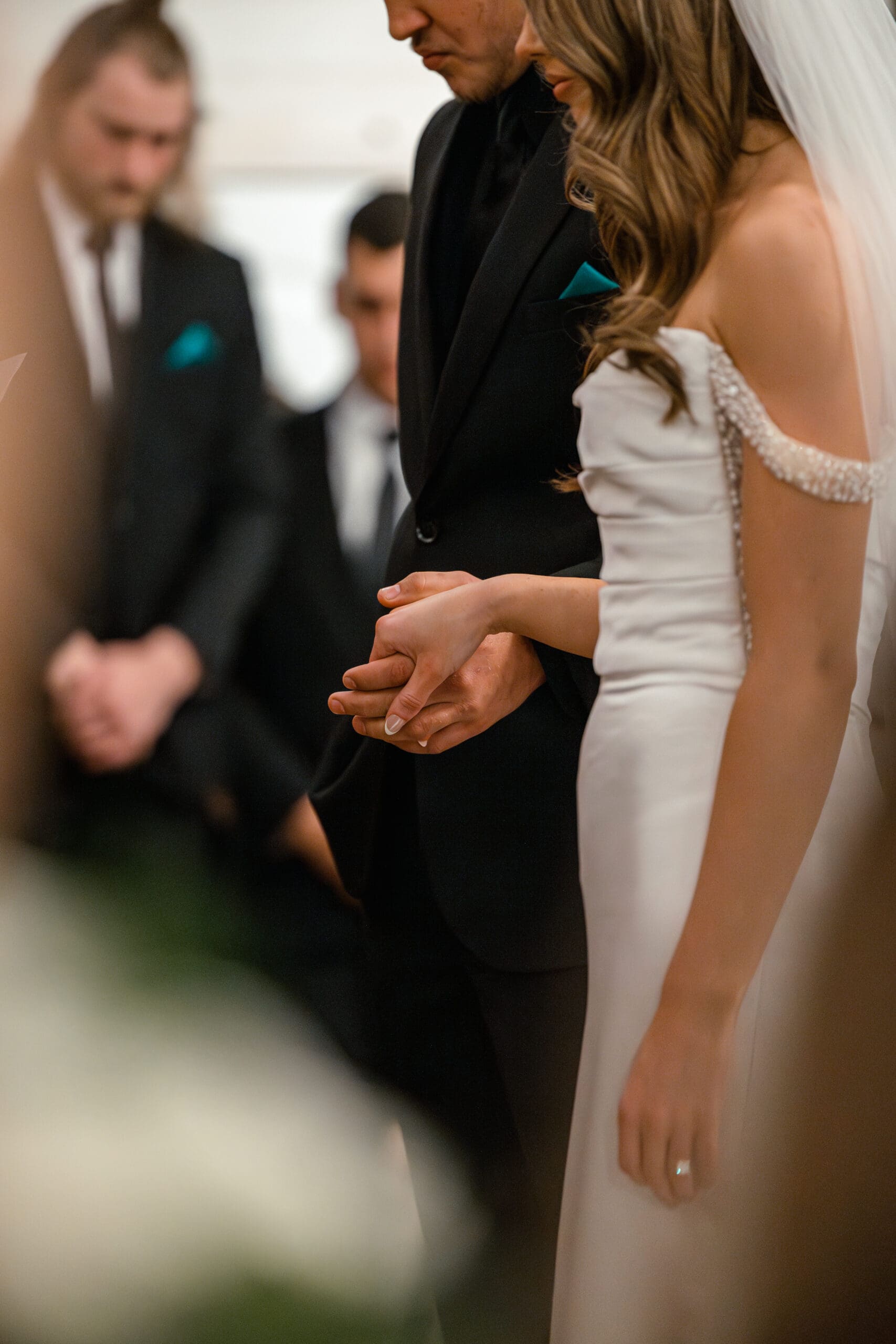 Bride and groom holding hands and praying during their winter wedding ceremony at The Silver Spoon Barn