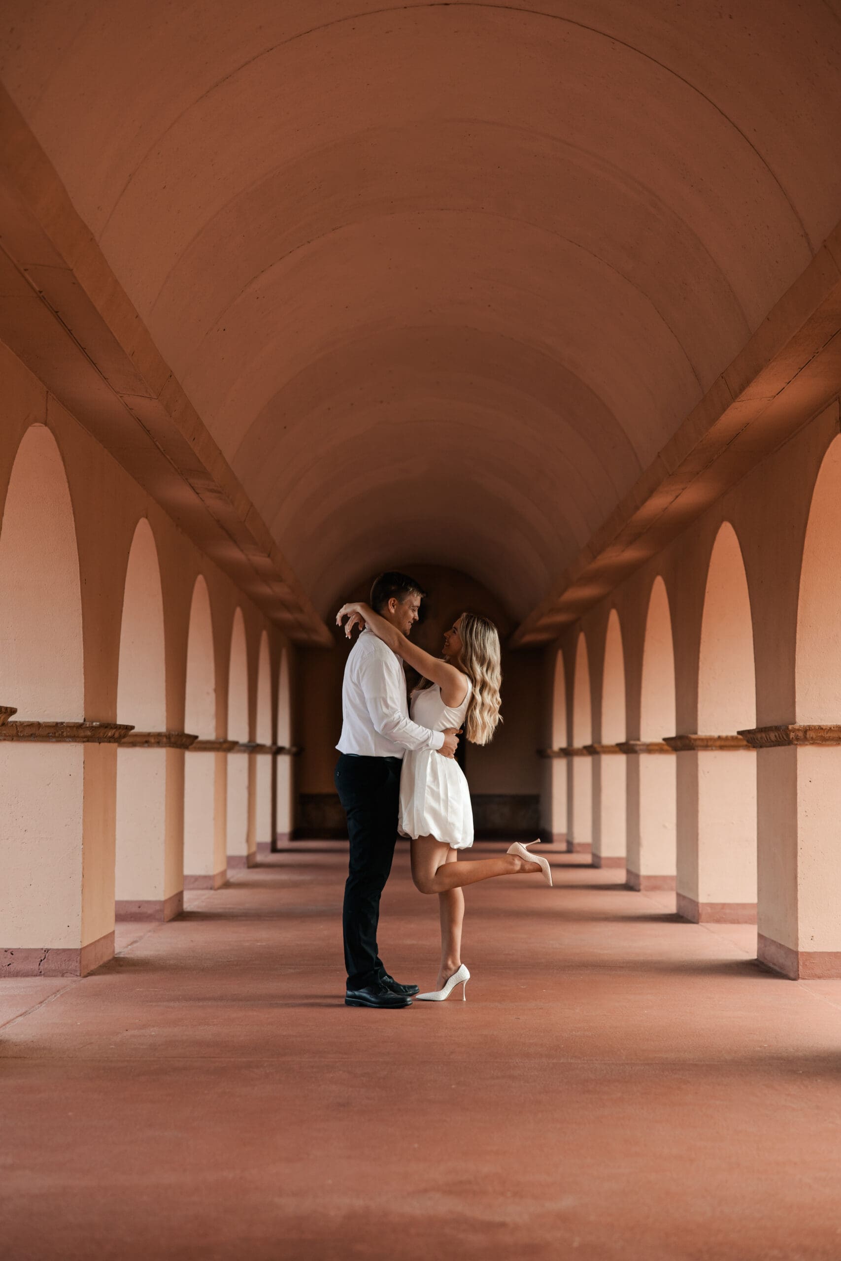 Engagement photo of couple walking under arches at Unity Village