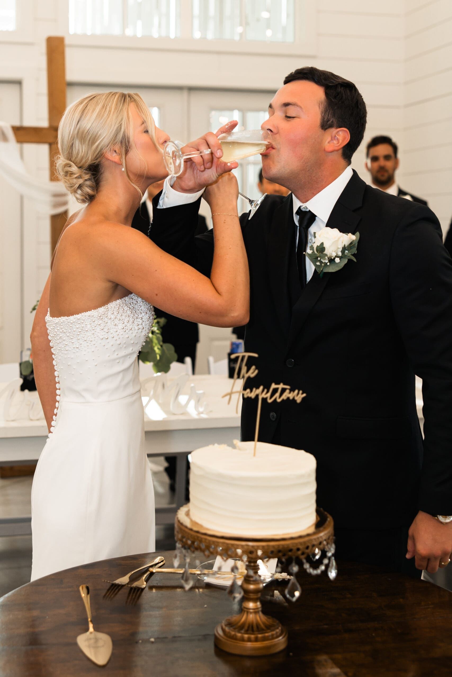 Bride and groom cheers with champagne after cake cutting Barn at Grace Hill.