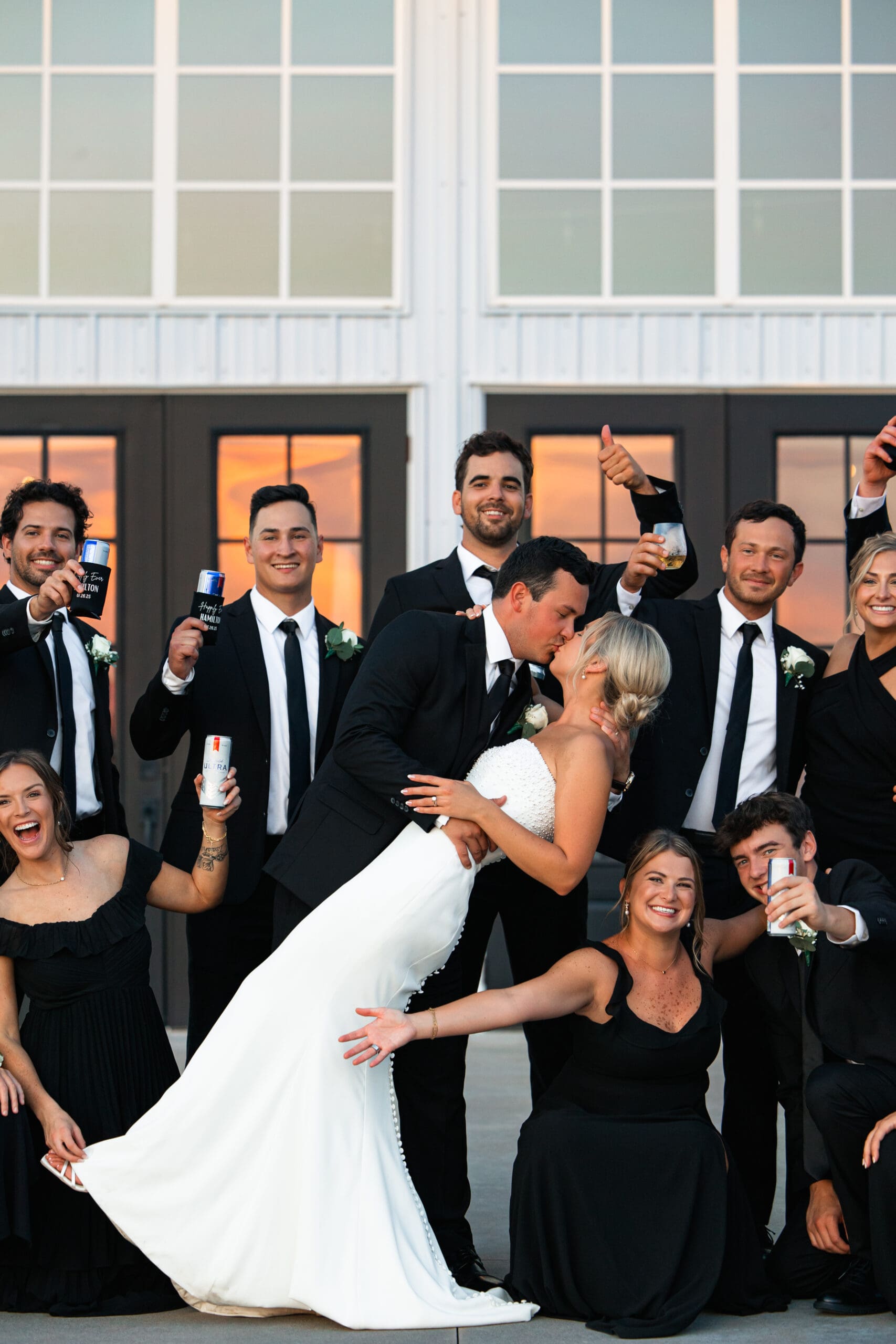 Bride and groom dip kiss with bridal party cheering Barn at Grace Hill.