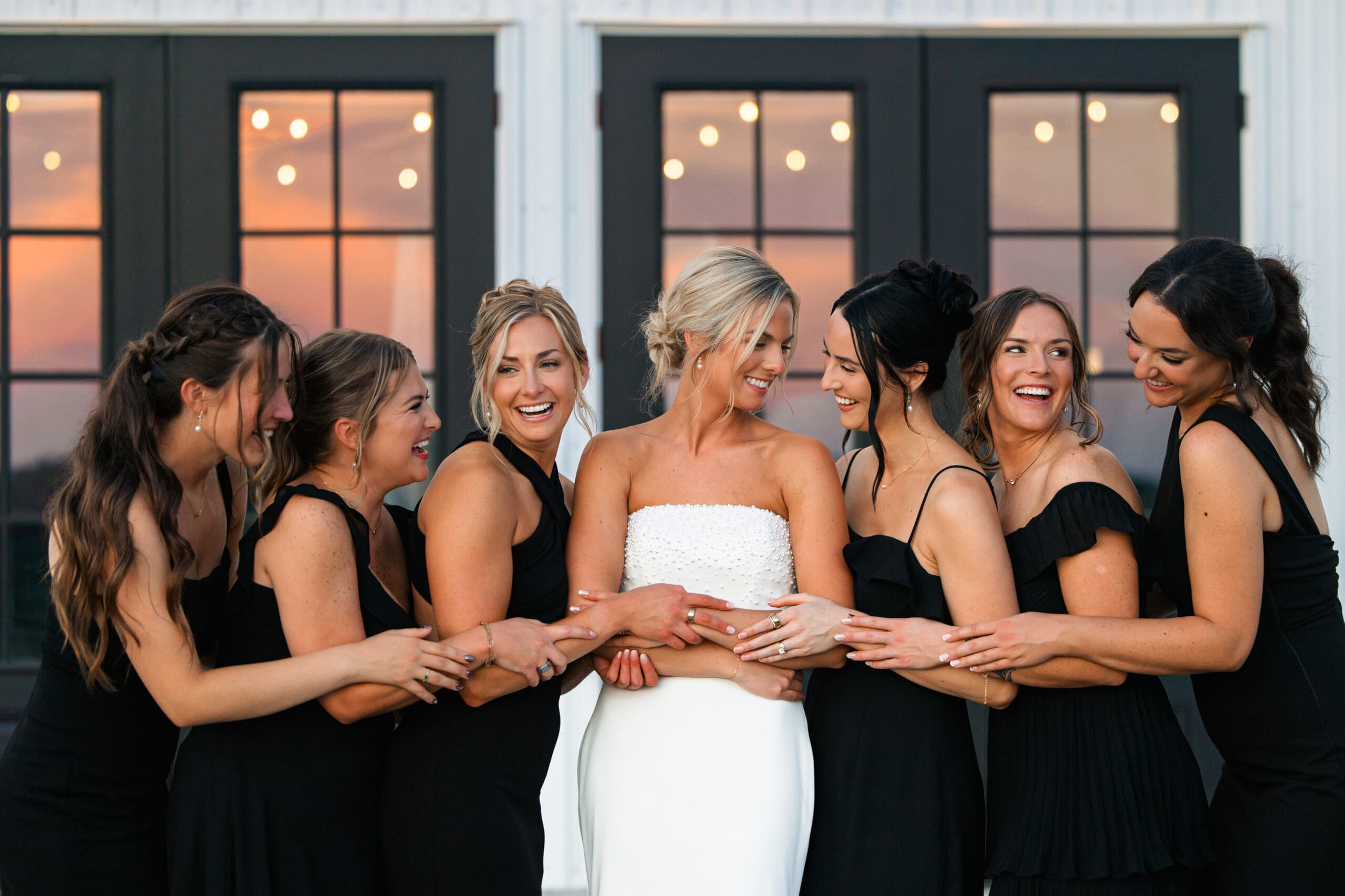 Bride hugging bridesmaids during golden hour Barn at Grace Hill.