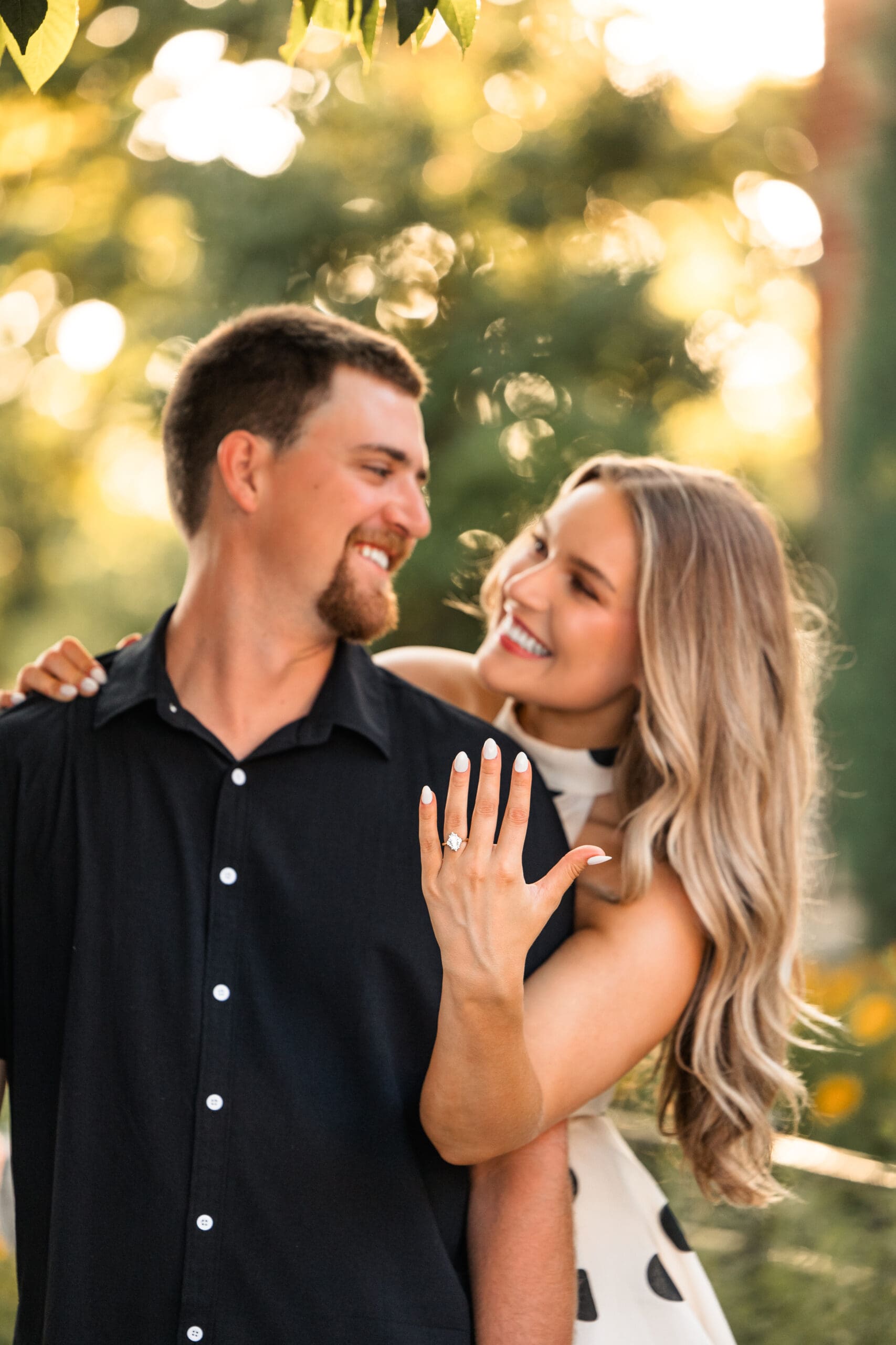 Bride shows off her engagement ring while leaning into groom. Wichita Wedding Photographer