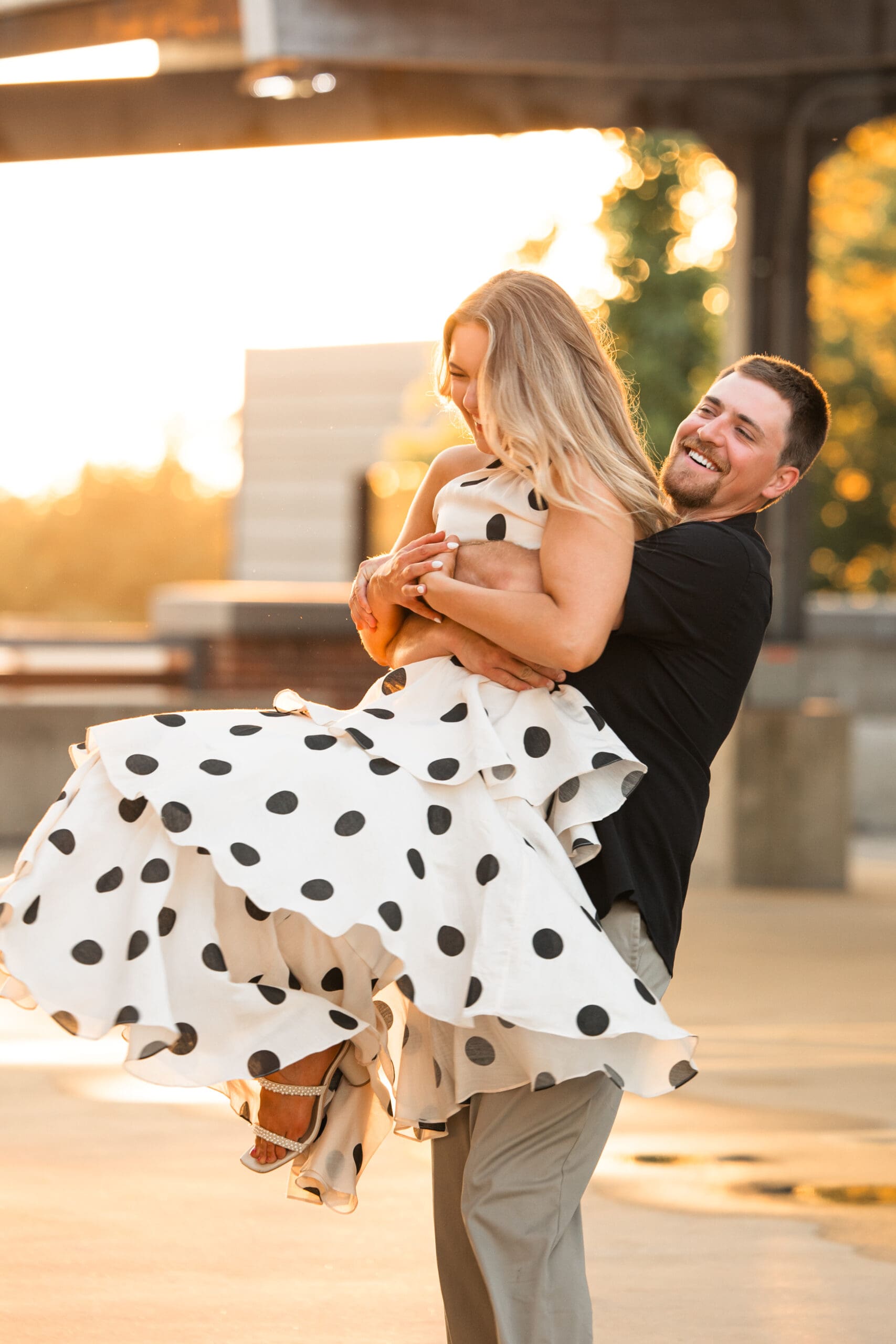 Groom spins bride with laughter on a rooftop parking garage.