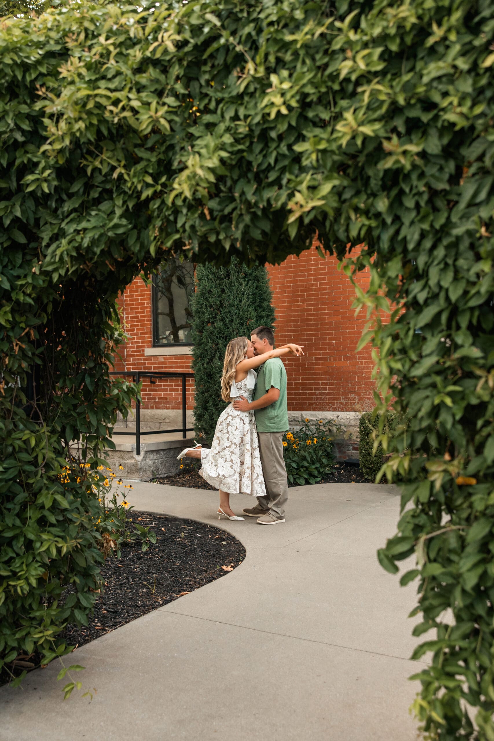Intimate kiss framed creatively through foreground details. Wichita Engagement Photographer