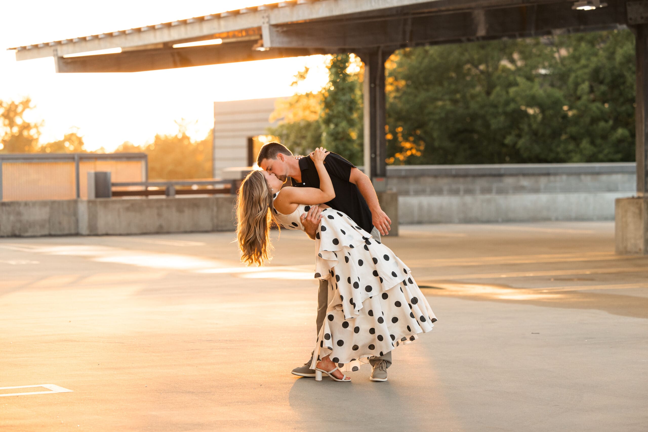 Groom dips and kisses bride with dramatic pose on rooftop.