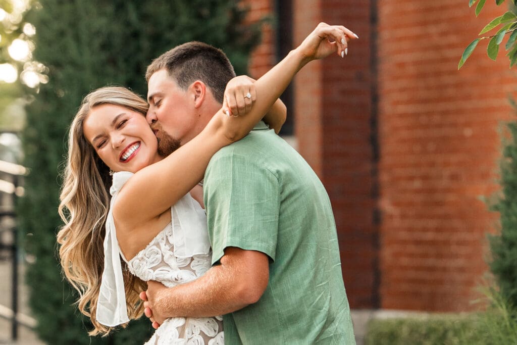 Groom kisses bride while she wraps her arm around his neck, captured by Wichita, KS, engagement photographer.