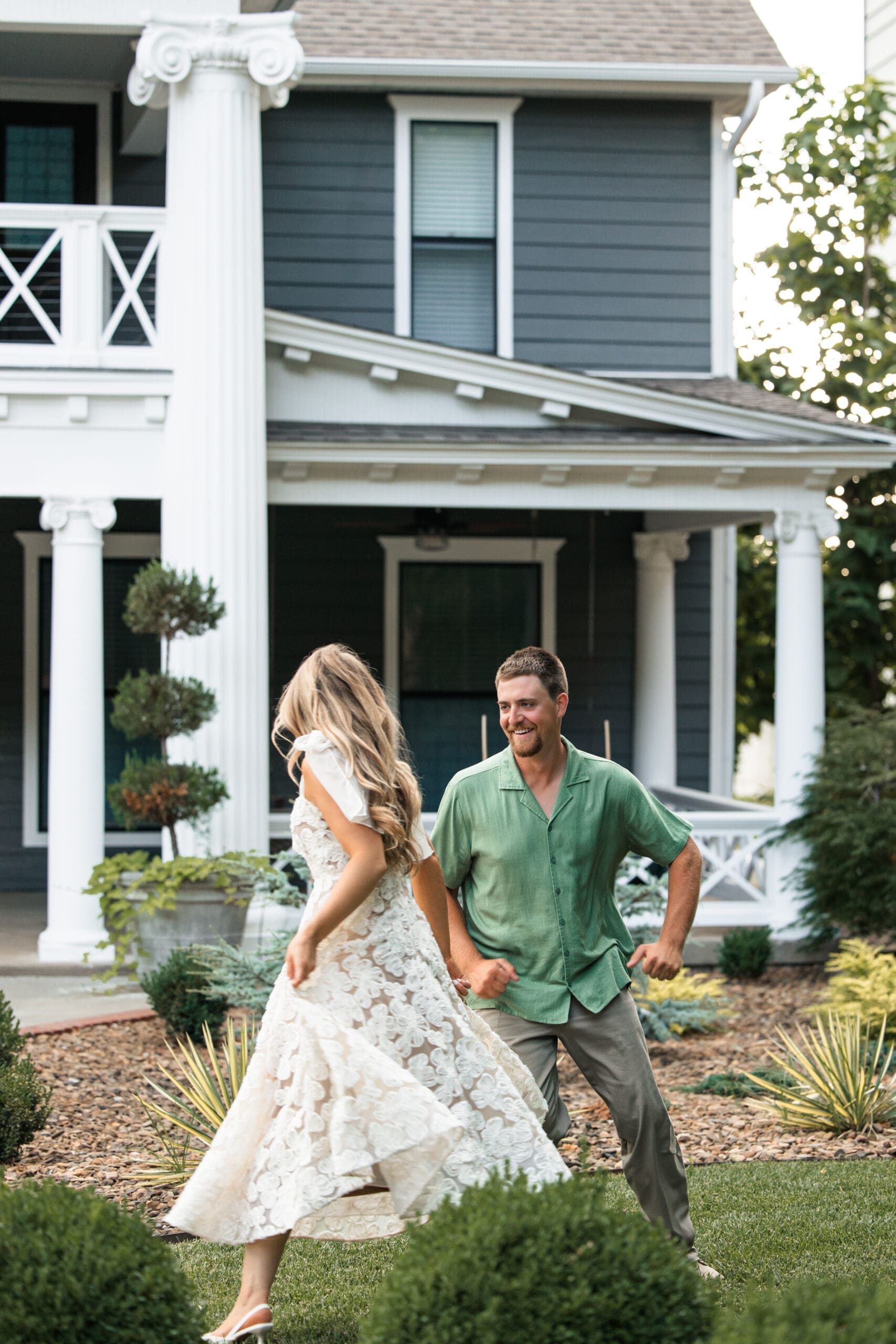 Bride and groom run playfully through the yard, laughing together. Wichita Engagement Photographer
