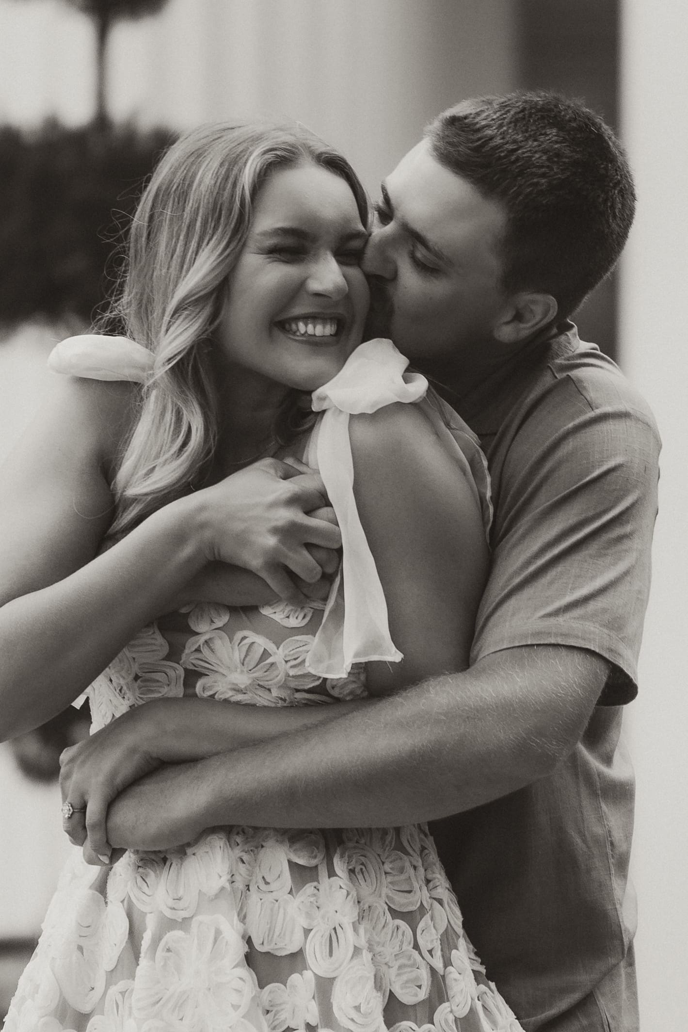 Close-up of groom kissing bride’s cheek while hugging her from behind. Wichita Engagement Photographer
