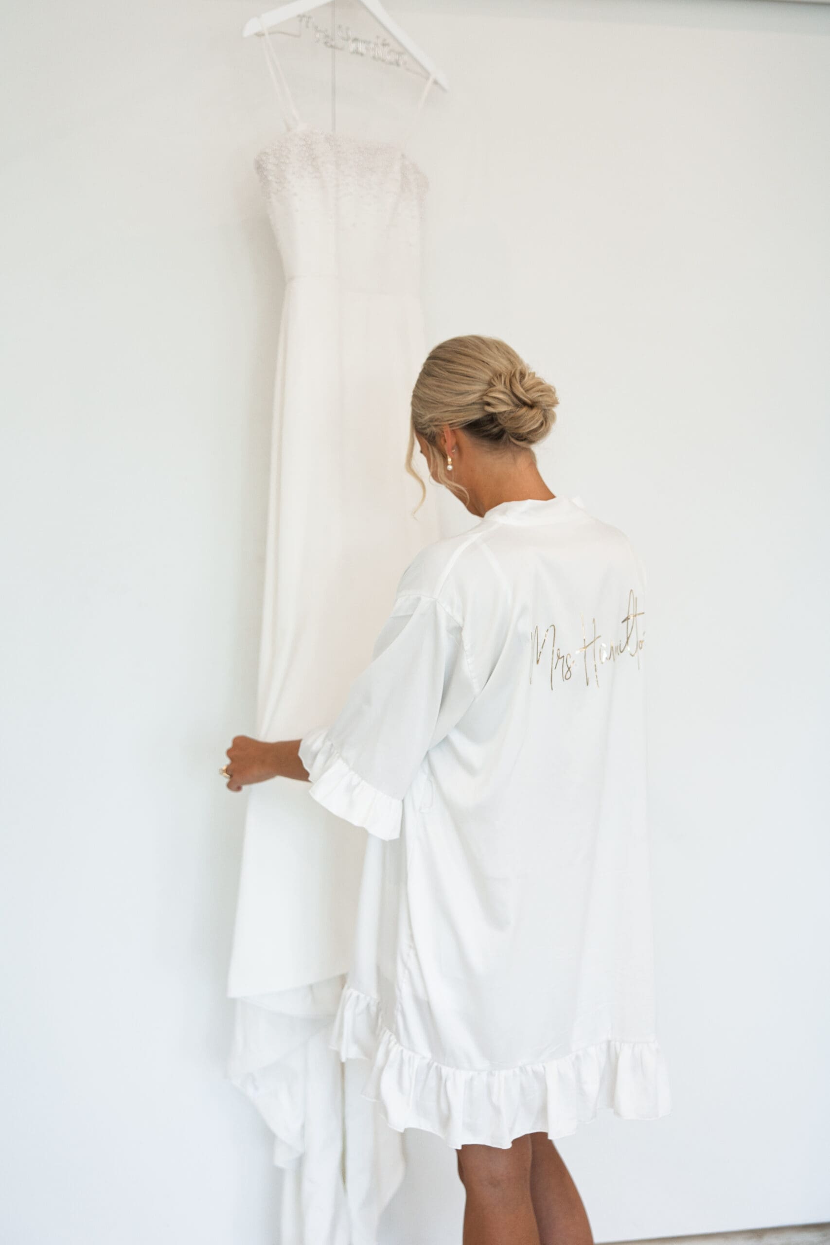 Bride in robe looking at wedding dress 