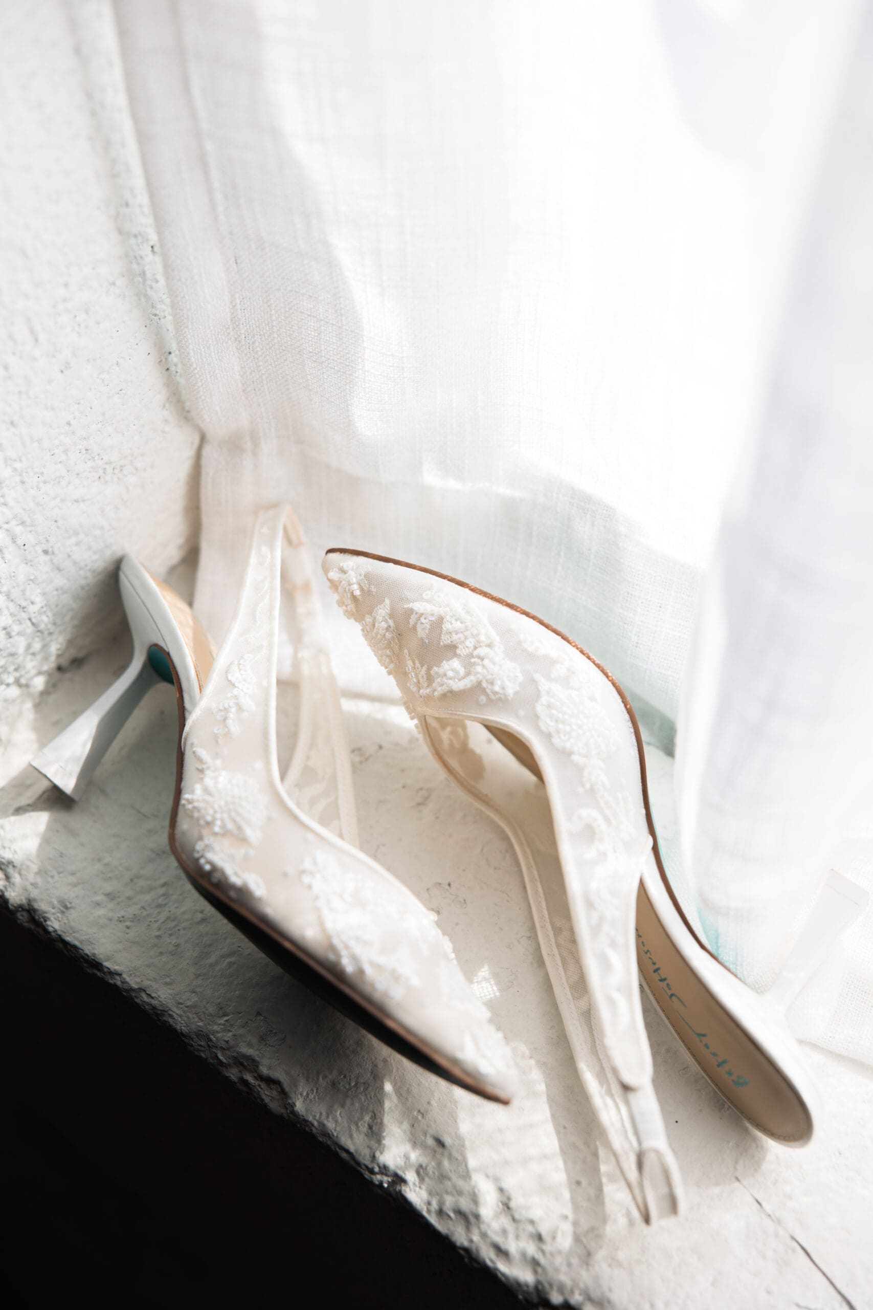 Lace bridal heels sitting on a bright window ledge at Stone Manor on 79th, photographed by Wichita wedding photographer Briana Jewell Photography