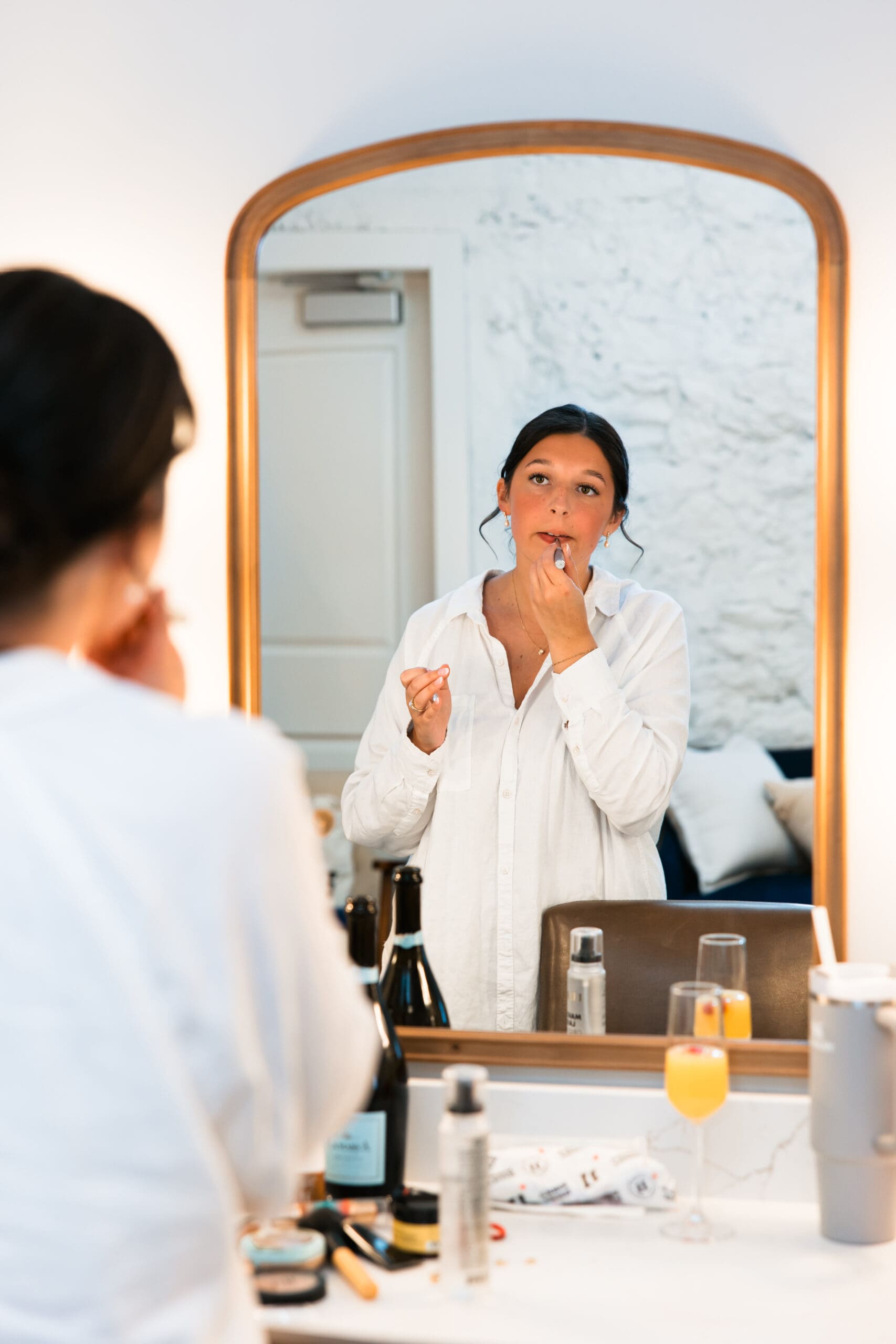 Bride getting ready and applying lipstick in the bridal suite mirror at Stone Manor on 79th in Overland Park, Kansas.
