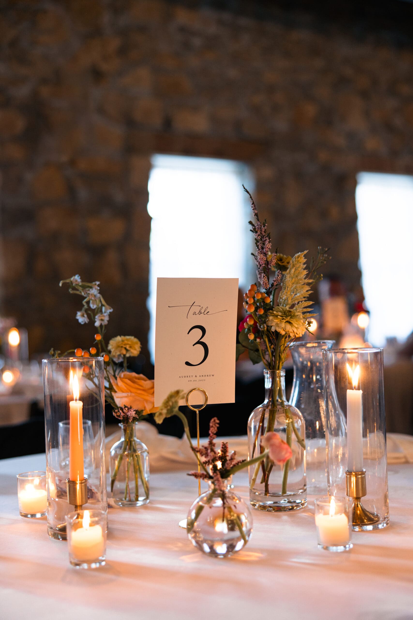 Romantic wedding table centerpiece with florals, candles, and minimalist table number at Stone Manor on 79th in Overland Park, captured by Wichita wedding photographer Briana Jewell Photography