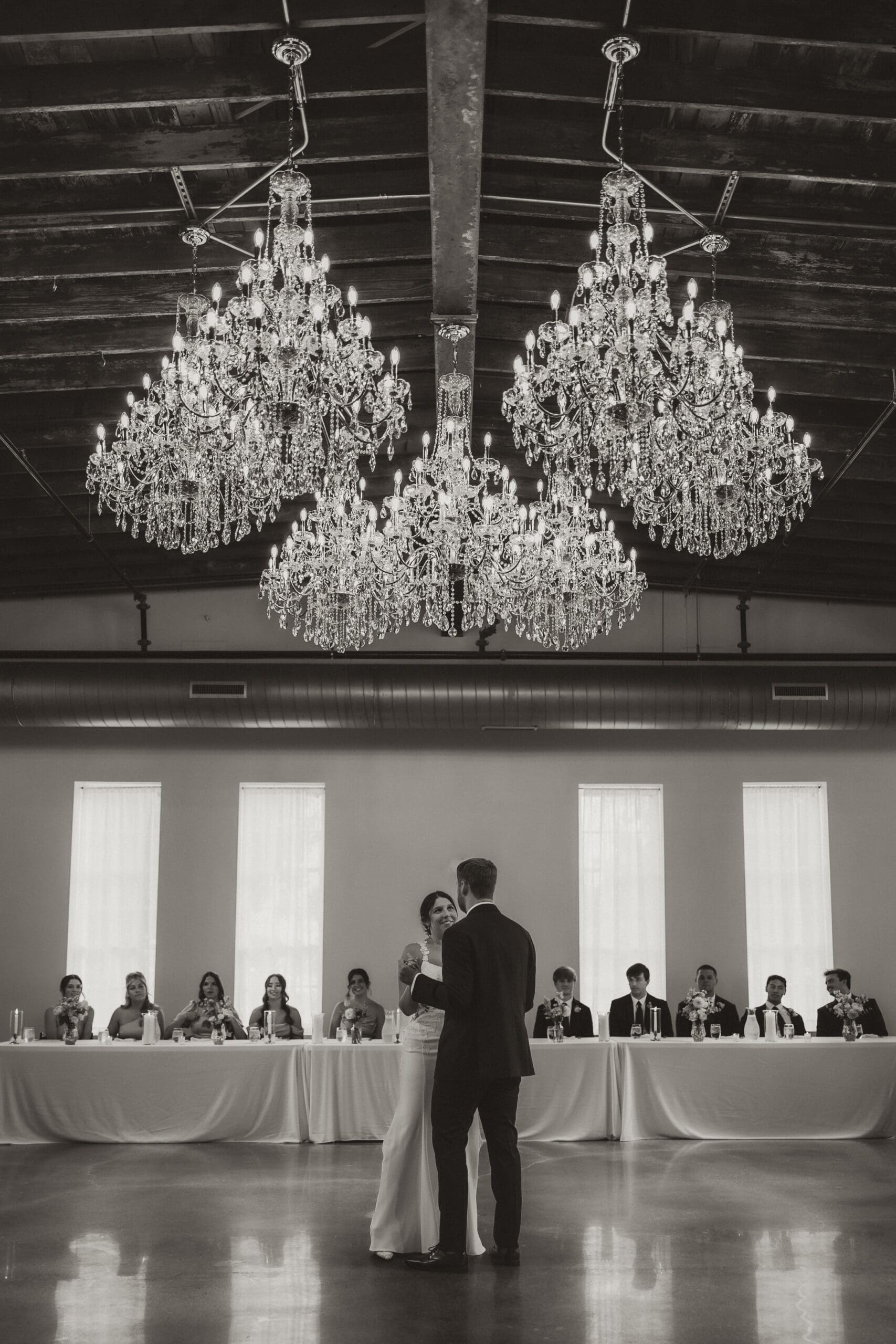 Bride and groom share their first dance beneath sparkling chandeliers at Stone Manor on 79th, photographed by Kansas wedding photographer