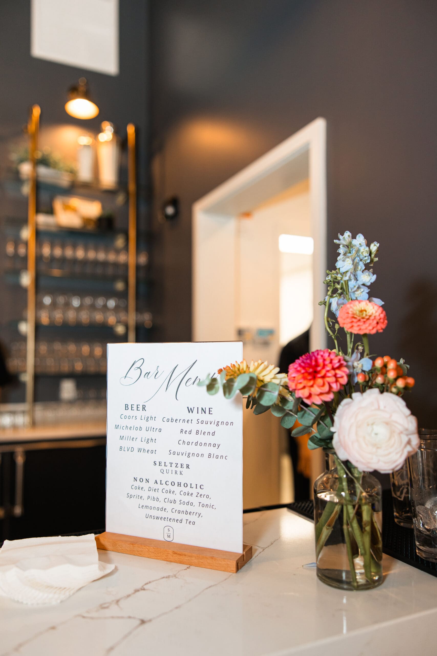 Elegant wedding bar menu and colorful floral arrangement at Stone Manor on 79th in Overland Park, captured by Wichita wedding photographer