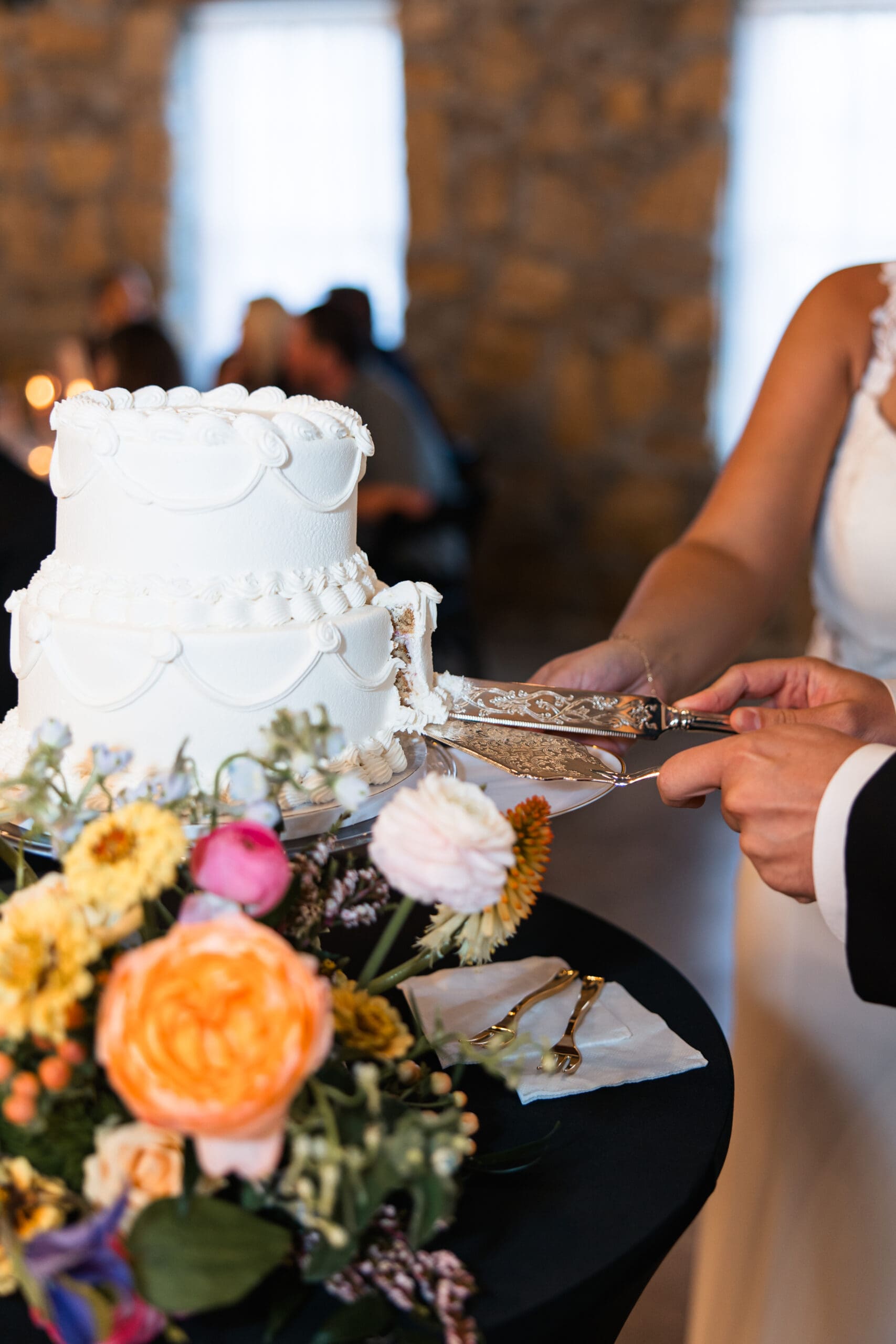 Elegant close-up of the bride and groom slicing their wedding cake with vintage gold server at Stone Manor on 79th in Overland Park, Kansas.