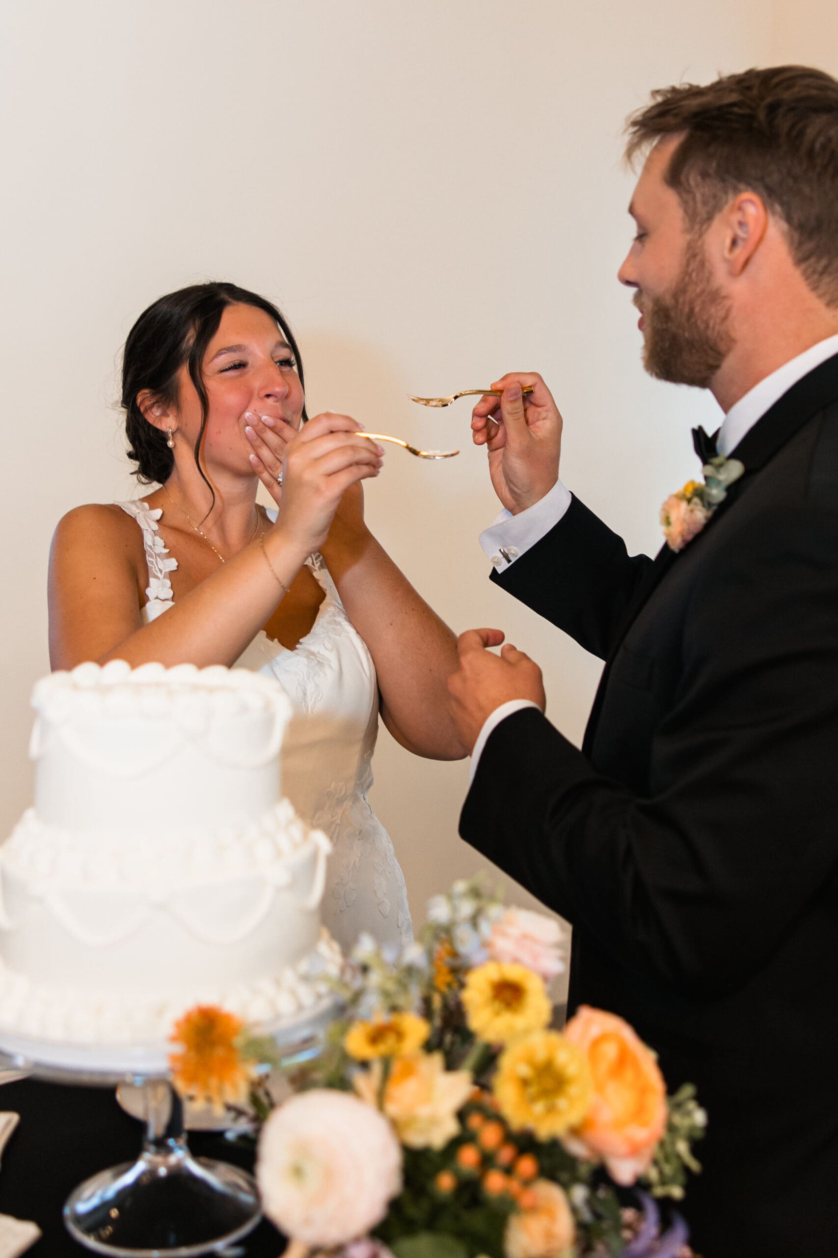 Bride and groom feed each other wedding cake and share a laugh during their reception at Stone Manor on 79th in Overland Park, Kansas.