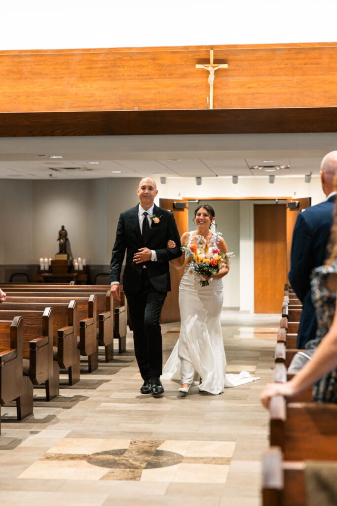 Bride walking down the aisle with her father at Holy Spirit Catholic Parish in Overland Park, Kansas