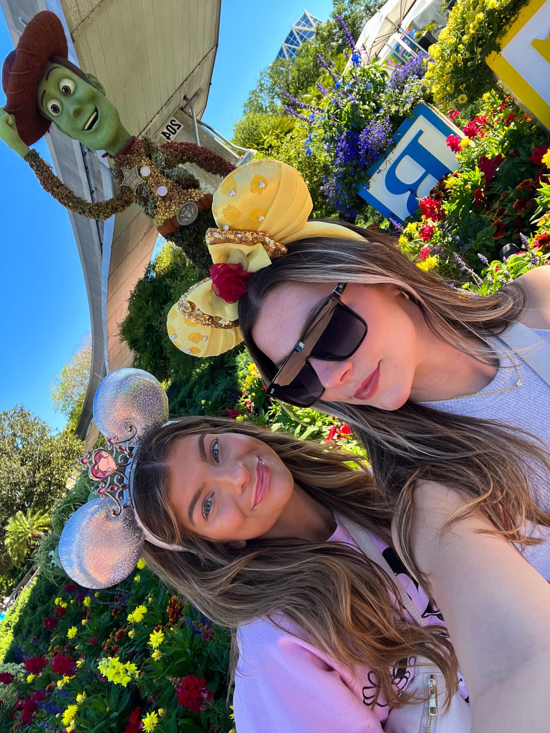 Two friends in Minnie Mouse ears smiling in front of Woody topiary at Epcot Flower & Garden Festival Disney World – fun, colorful photo moment amid blooming gardens in Orlando