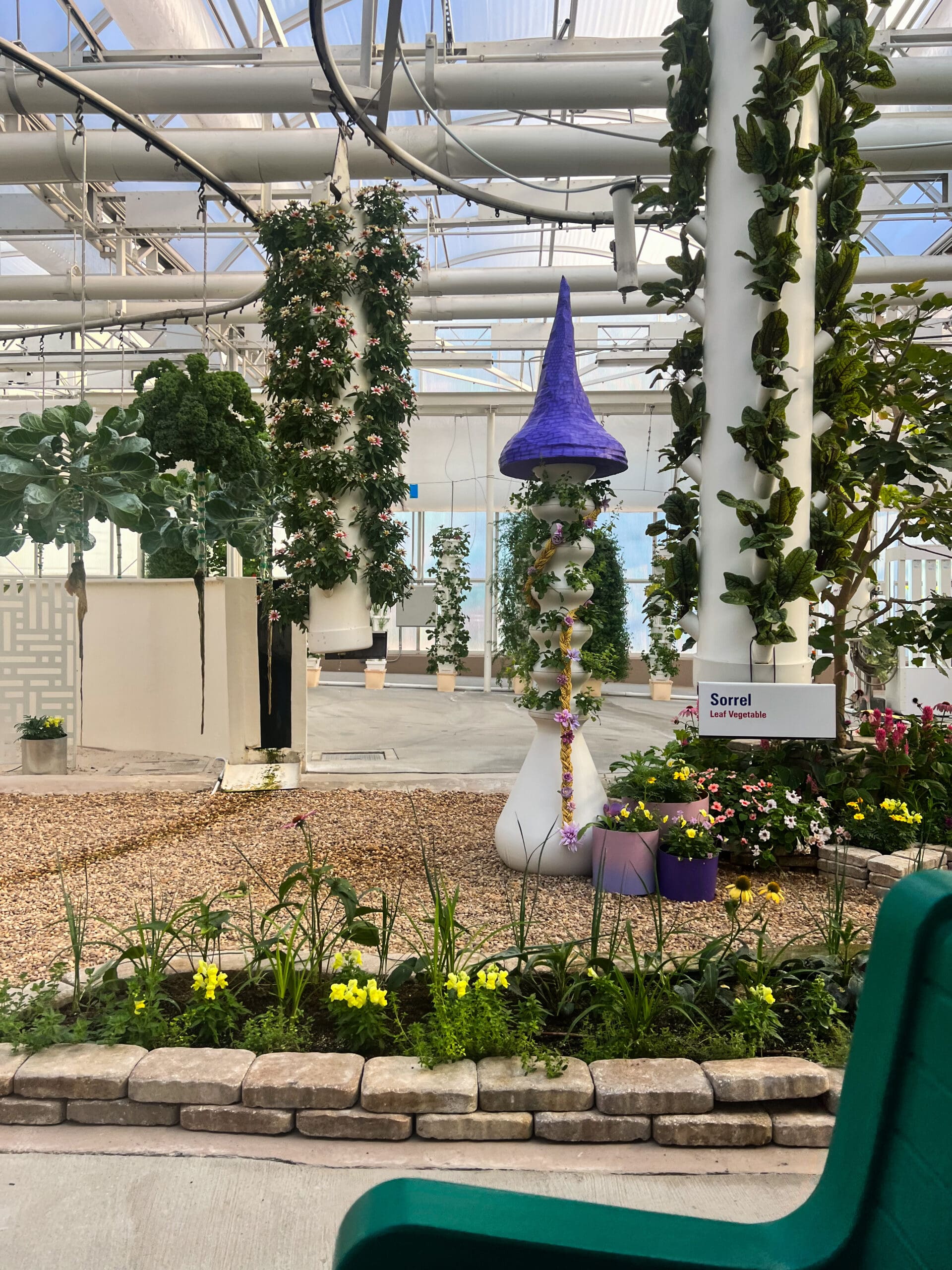 Tall purple topiary surrounded by hanging flowers and leafy greens in Epcot's Living with the Land greenhouse – whimsical plant magic from Flower & Garden Festival Orlando