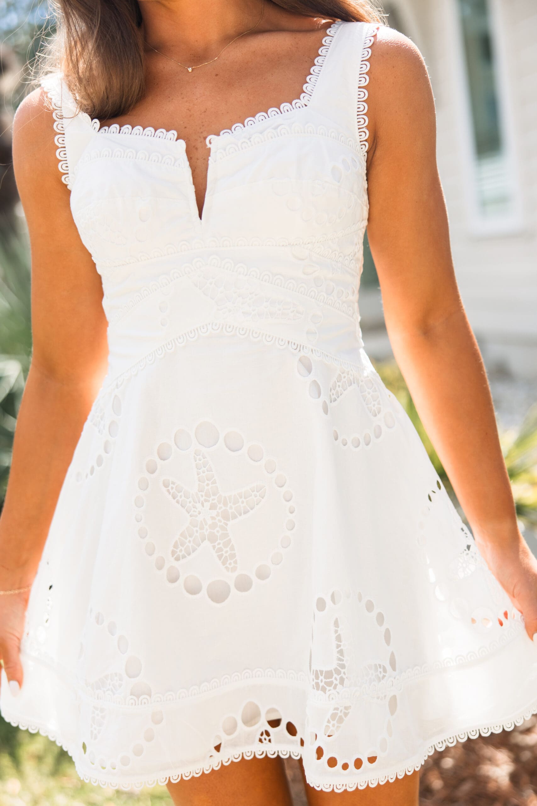 Close-up of a white eyelet sundress with starfish cutout detail from the Fairhope Collection by Ave & Liv, photographed during a Fairhope Alabama photoshoot