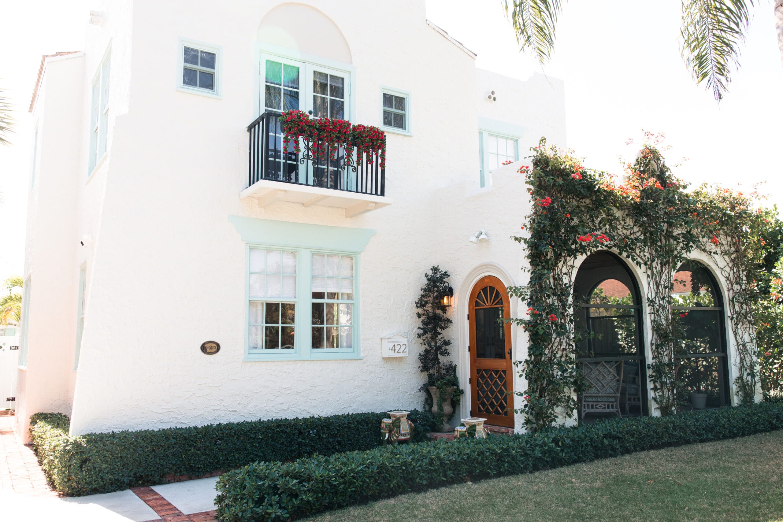 Charming white Mediterranean villa exterior with turquoise accents and blooming bougainvillea at The Pink Palm Beach historic cottages – perfect bachelorette stay