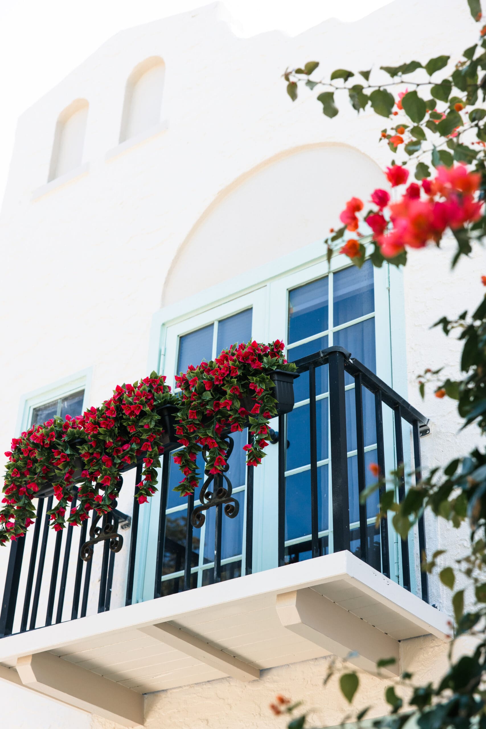 Romantic balcony overflowing with vibrant red bougainvillea at The Pink Palm Beach historic Mediterranean villa – ideal backdrop for bridal party photos