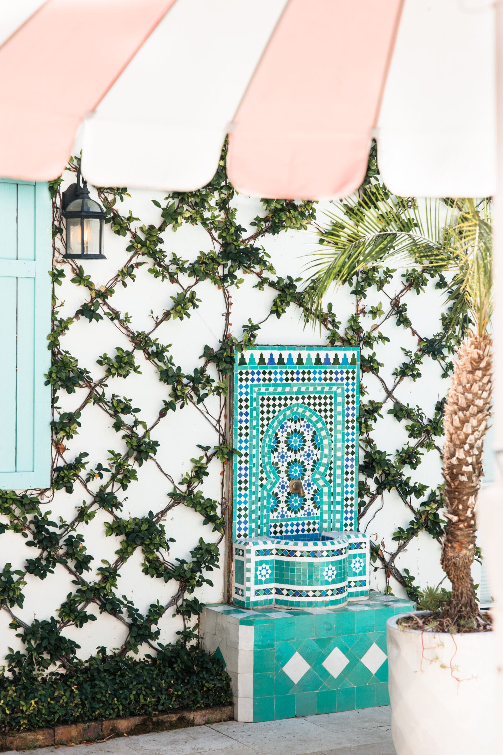 Stunning turquoise Moroccan mosaic fountain surrounded by ivy at The Pink Palm Beach pool area – luxurious girly touch for bachelorette getaways